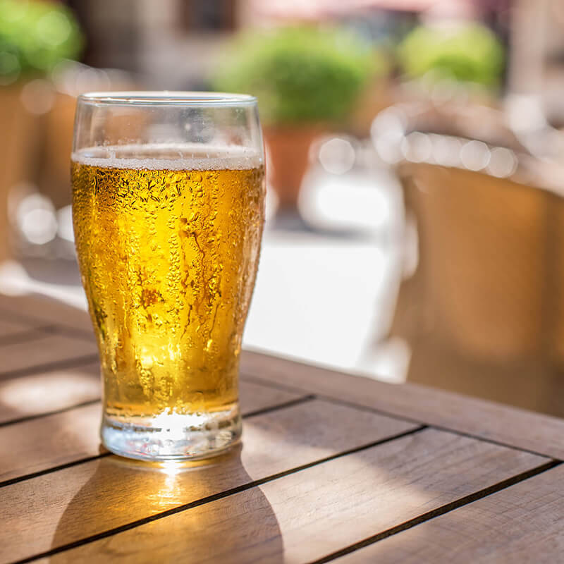 A glass of beer on a outside table.