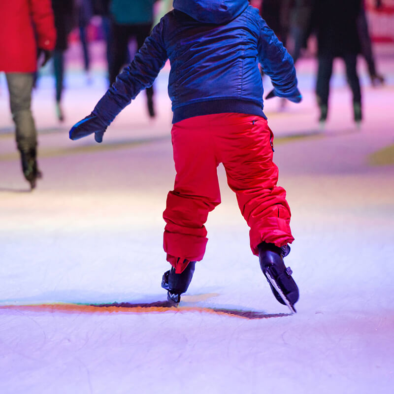 A kid ice skating at a rink.