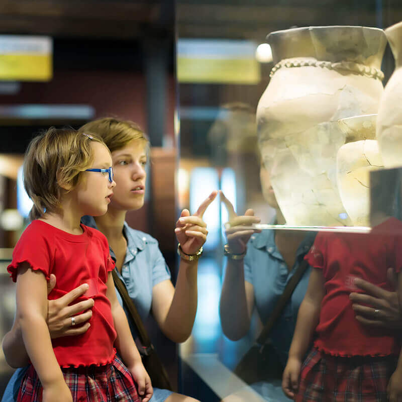 Two kids looking at ancient pottery in a museum.