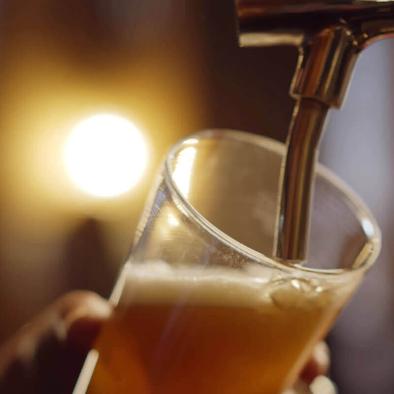 A glass of beer being filled up at a tap.