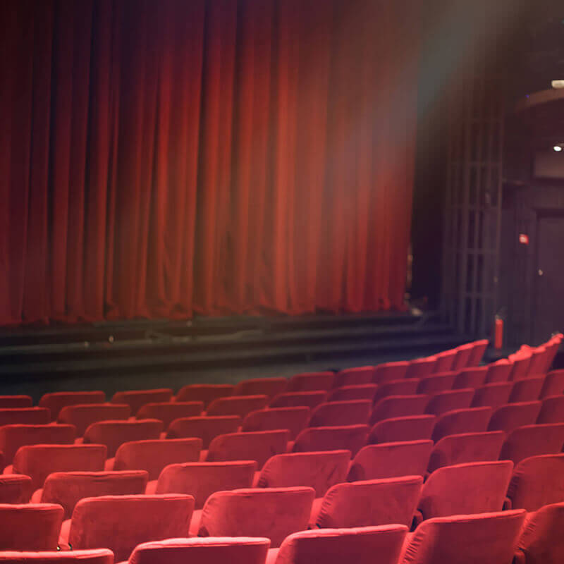 A performing arts center with red seats and a curtain closed.