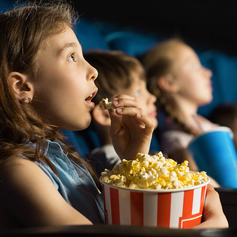 Kids eating popcorn in a movie theatre.