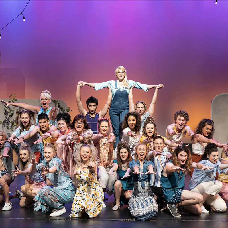 A group of theatre actors posing at the end of a show on stage.