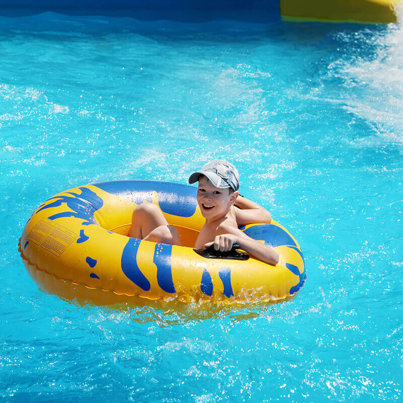 A smiling boy in an inner tube on a water slide.