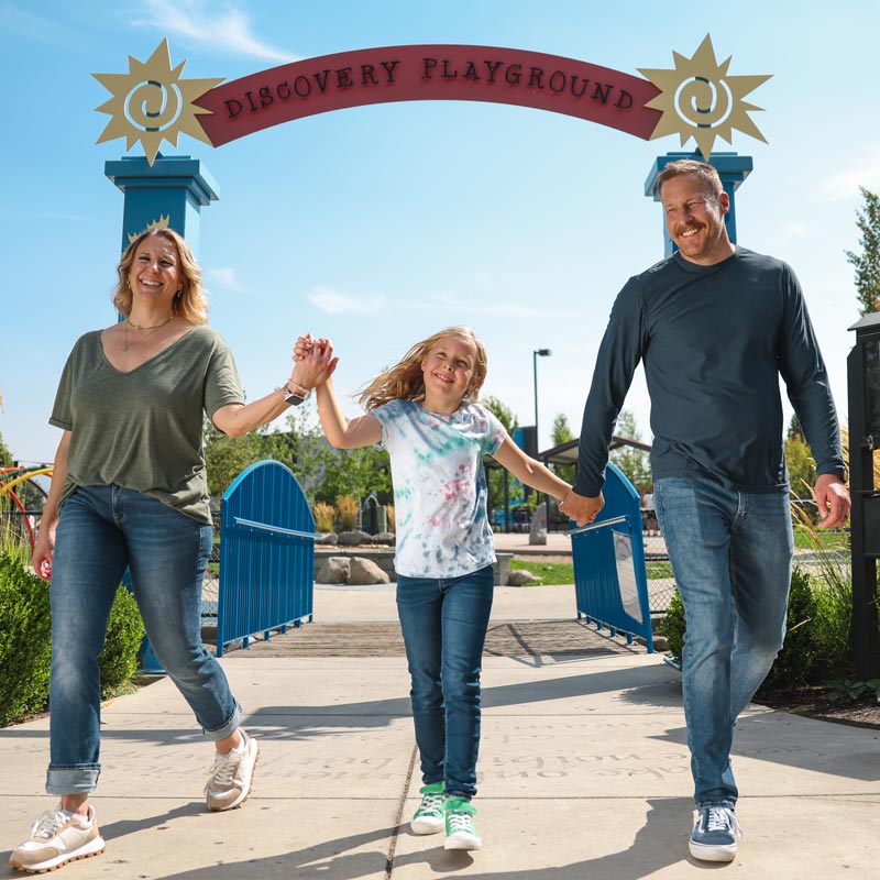 A family of three walking at Discovery Playground in Spokane Valley.